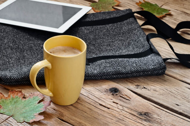 Cup of cappuccino with female woolen bag and tablet