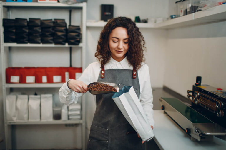 female worker packing coffee beans in a vacuum sealed bag