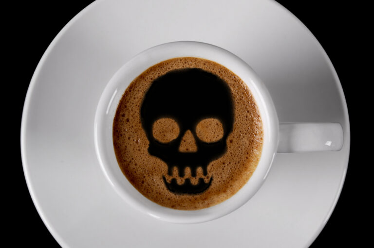 A cup of strong black coffee with a skull pattern.
