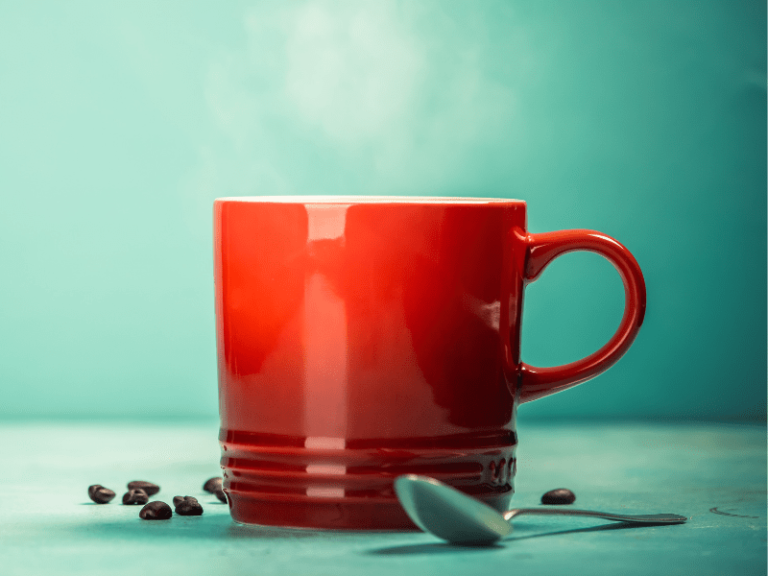 A glass mug on a table, with Coffee and coffee beans.