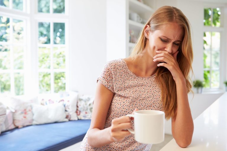 A woman drinking coffee that is bad tasting.