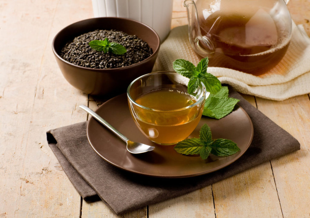 green mint tea in glass cup on wooden table
