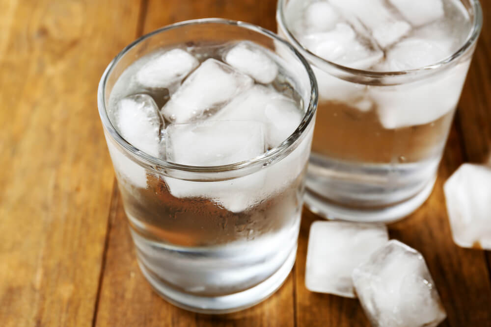A clear glass of water filled with ice cubes.