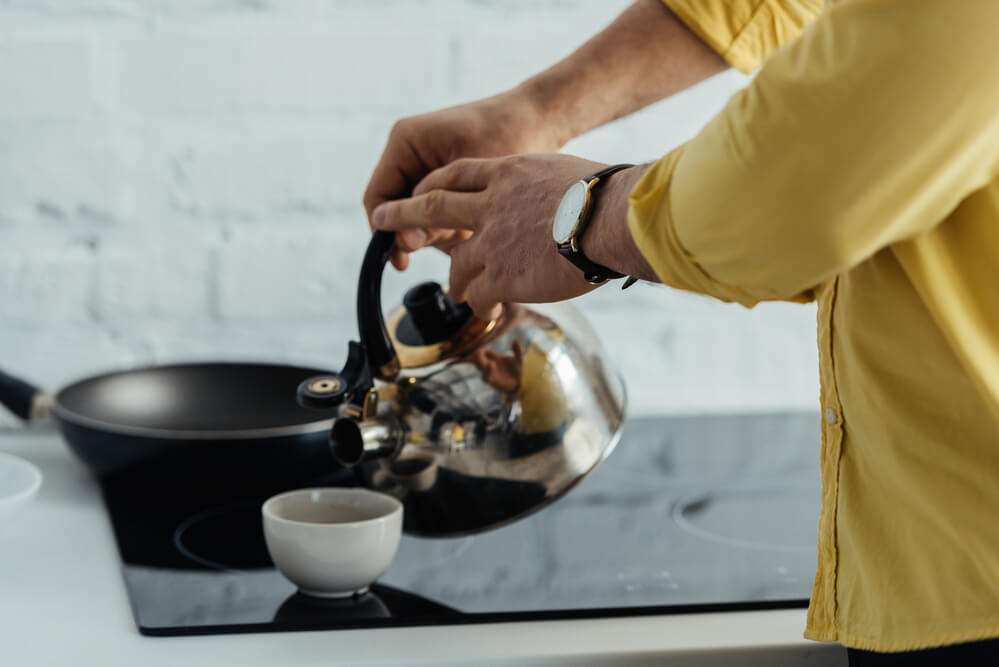 hot water from the kettle poured down to a cup