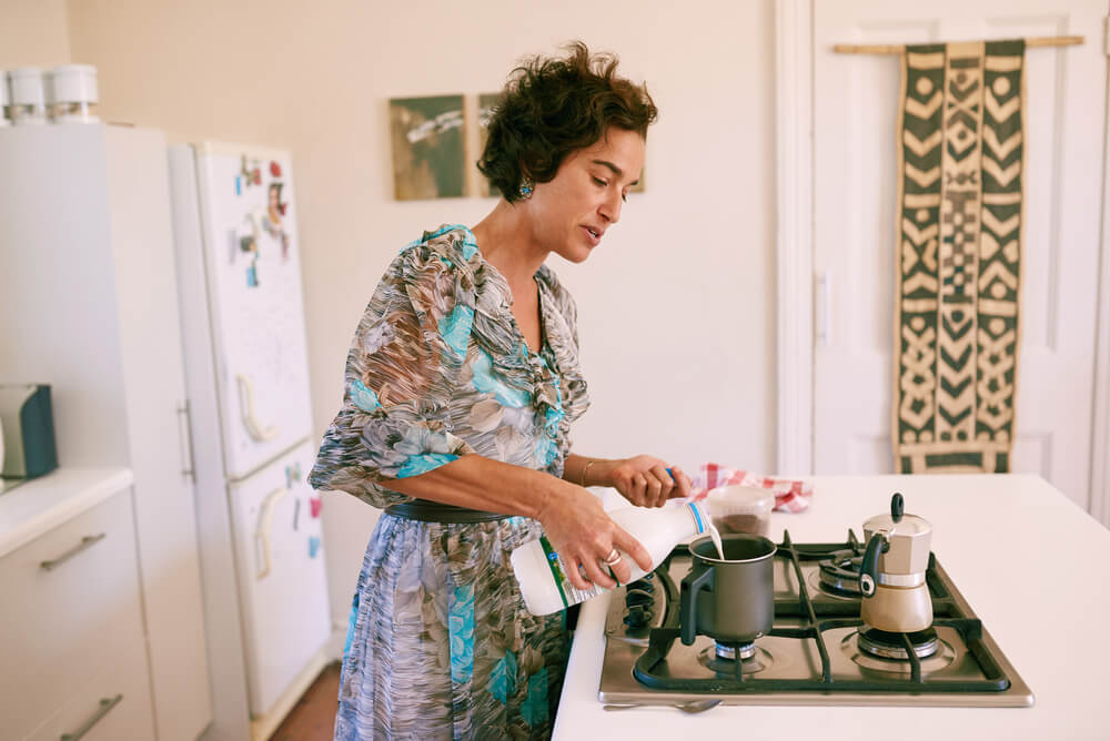Mature woman preparing a drink in her kitchen - What Is A Babyccino Drink