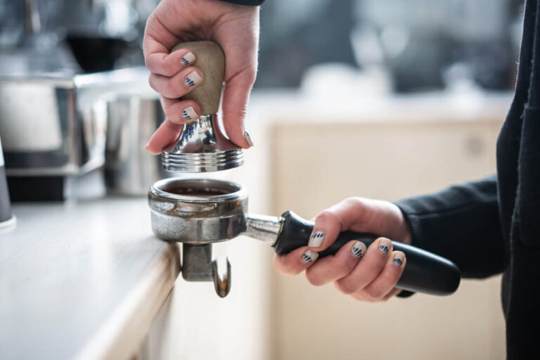 Barista presses ground coffee using tamper