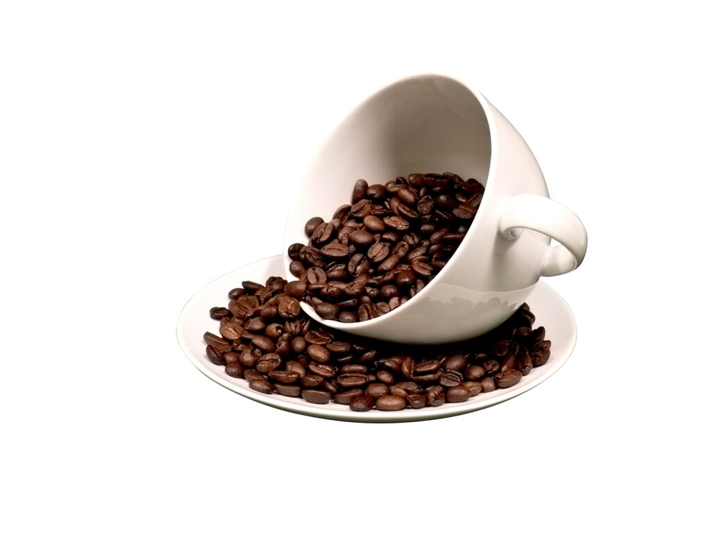 a white cup of coffee beans with coffee beans in a saucer.