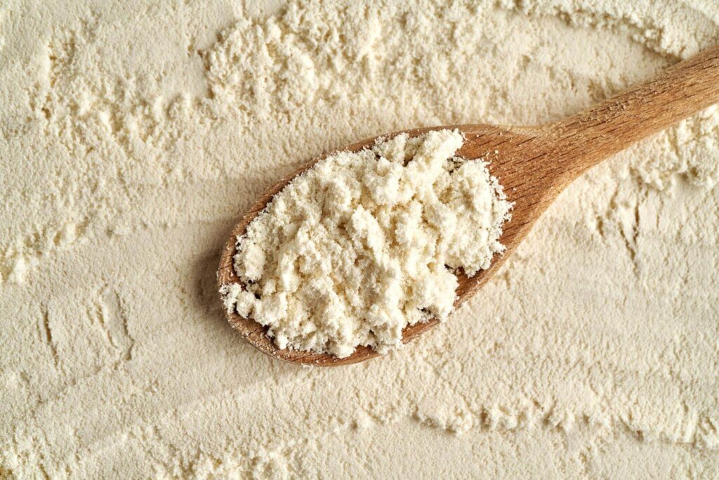 Whey protein powder on a wooden cooking spoon