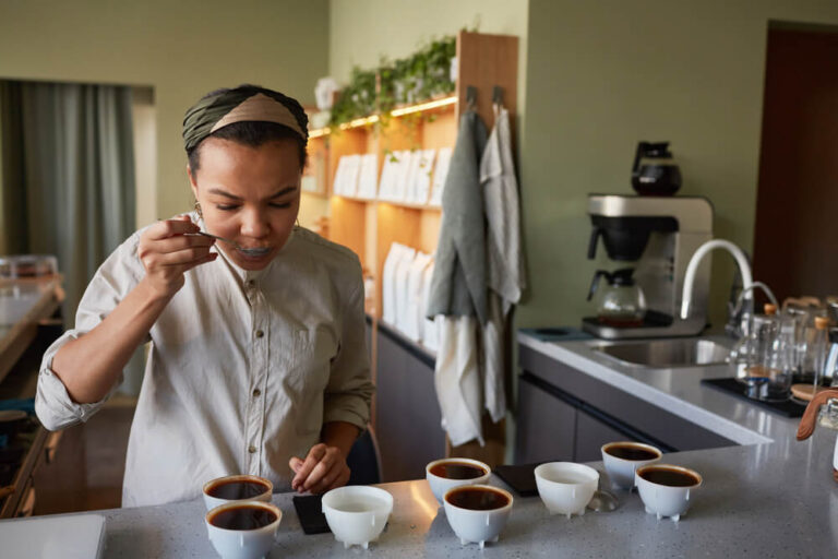 young African-American woman tasting coffee and assessing its quality