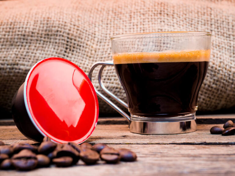 Cup of coffee and pods on wooden table