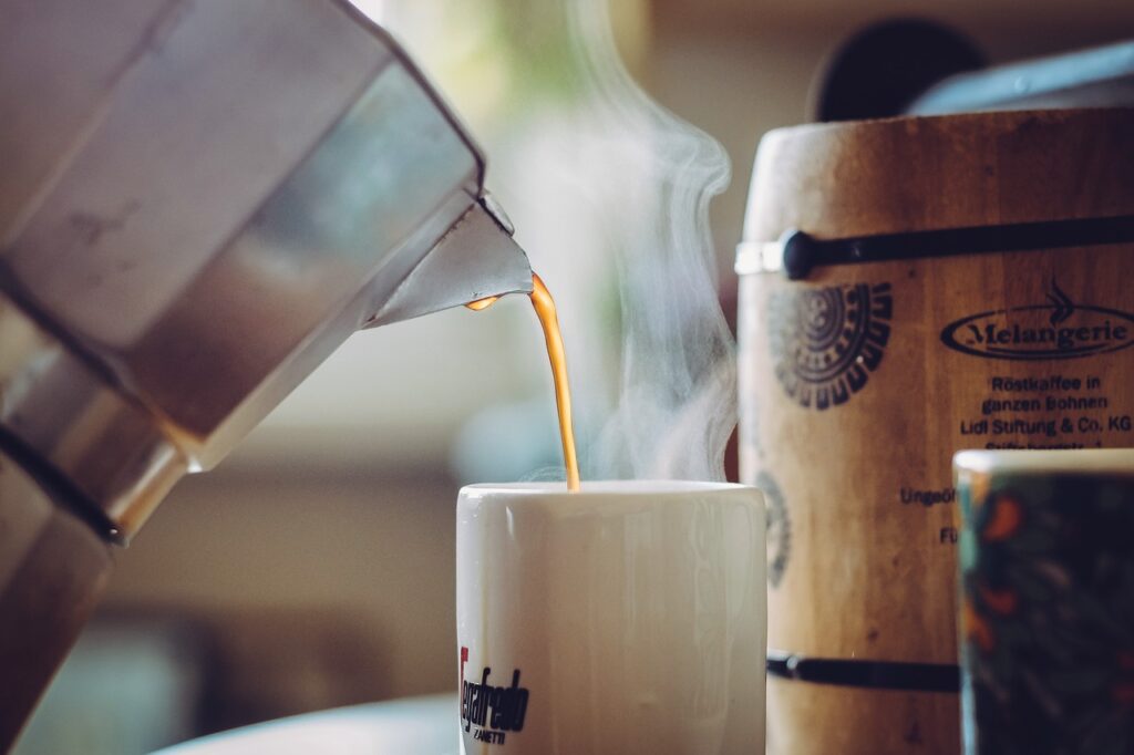 Pouring a newly brewed coffee on a white mug.