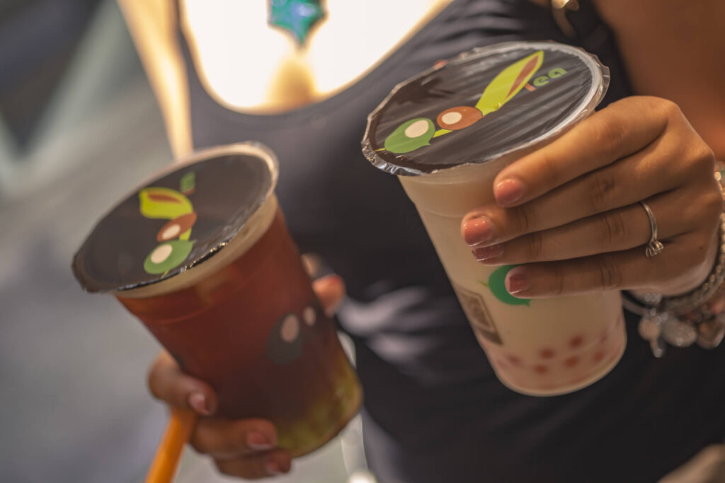 a woman holding two bubble teas