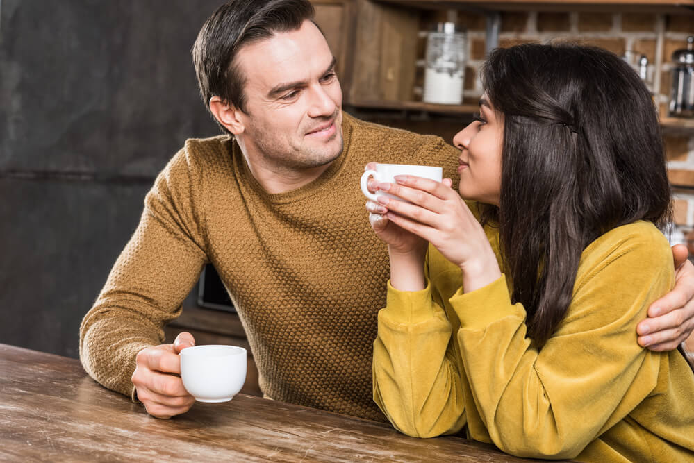 two couple looking at each other while holding a cup of coffee