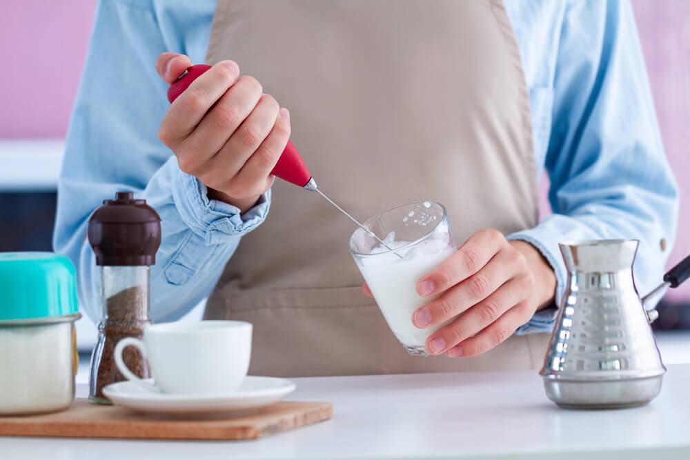 an unidentified person frothing milk for coffee