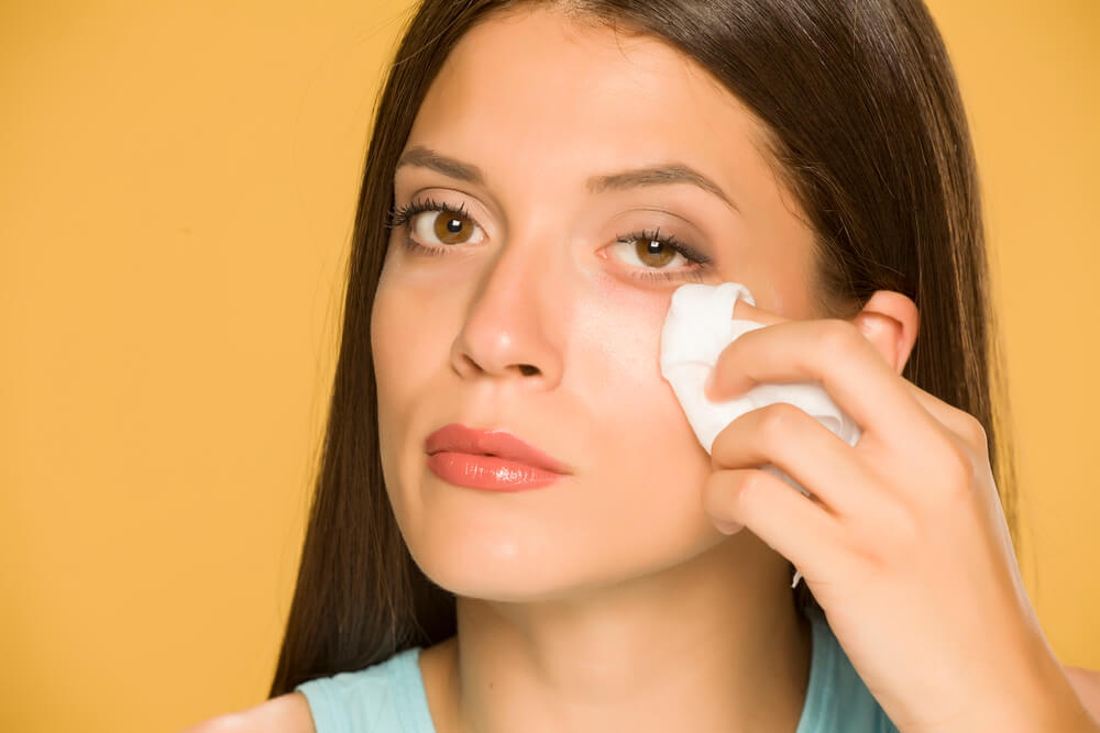 a woman carefully cleaning her face 