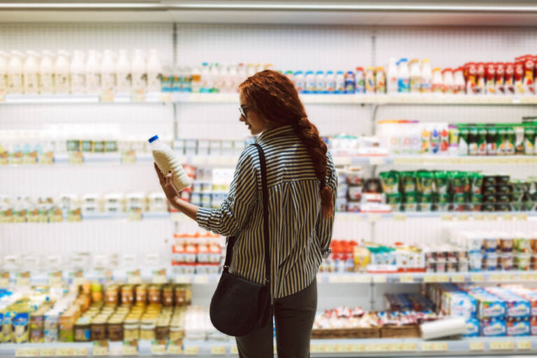 Pretty girl in eyeglasses and striped shirt holding milk bottle