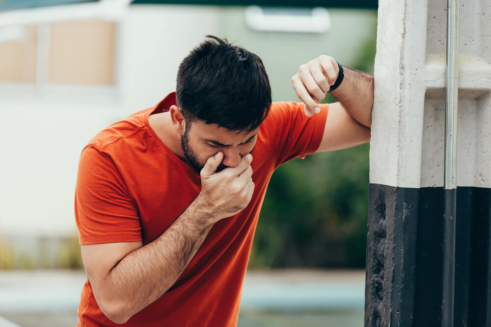 Portrait of young man sick vomiting outdoors