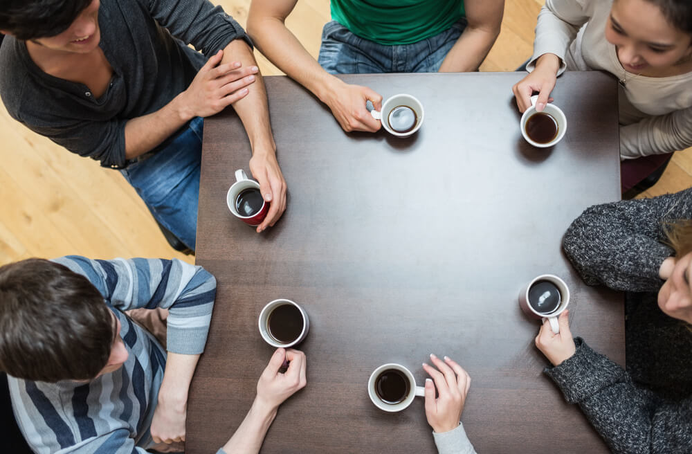 a group of people happily talking while holding a cup of coffee