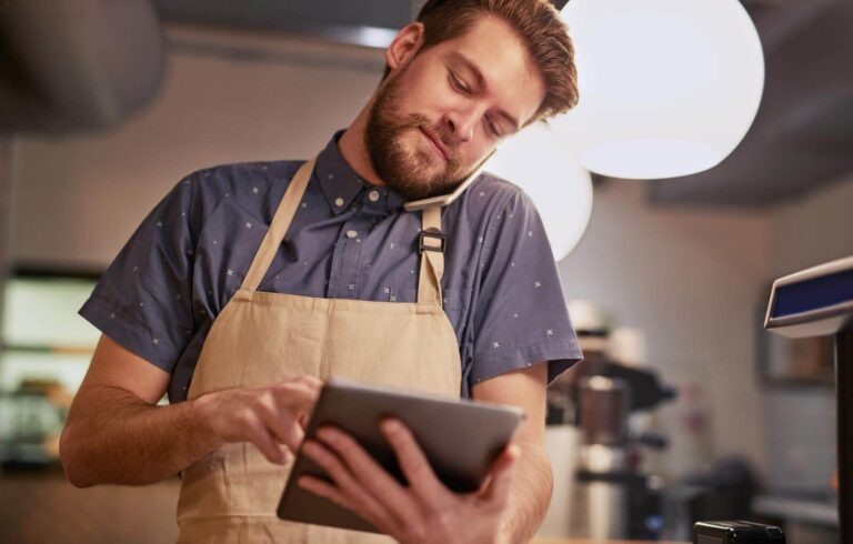 Shot of a young man using a digital tablet while working in a coffee shop - Is selling coffee online profitable
