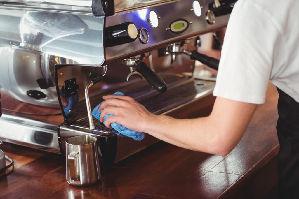 Barista cleaning coffee machine