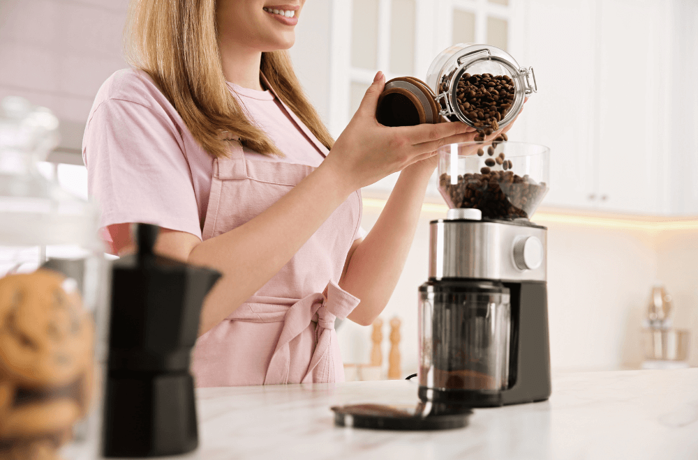 Woman pouring coffee beans in electric coffee grinder