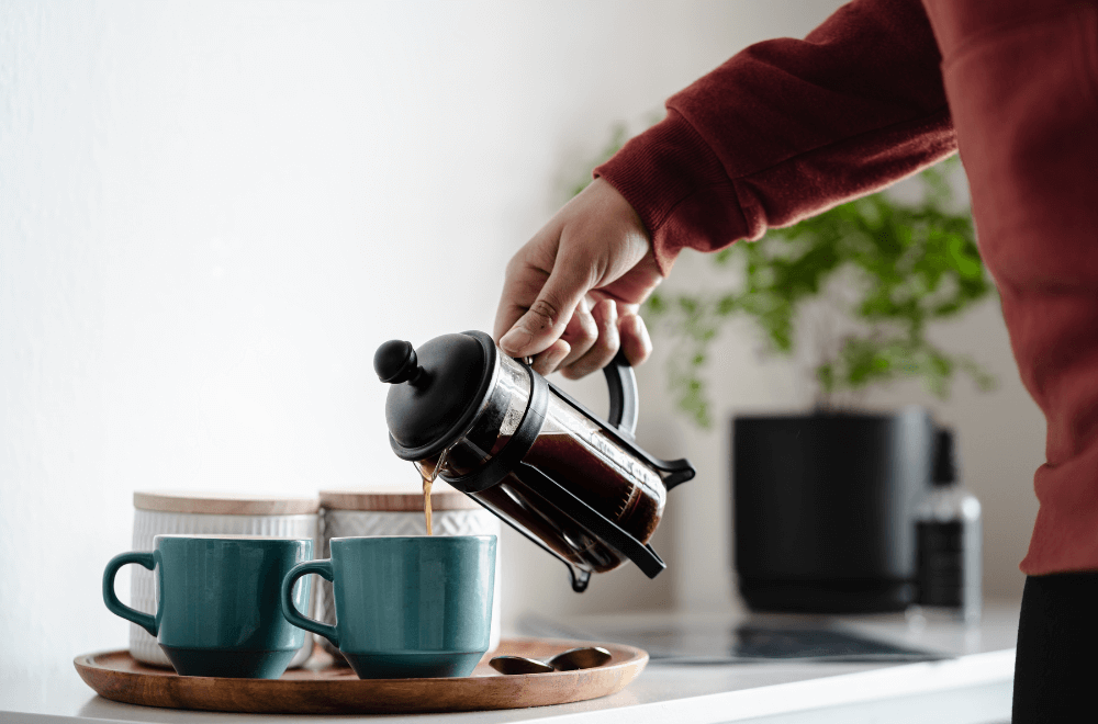 A woman pouring coffee in two cups at morning
