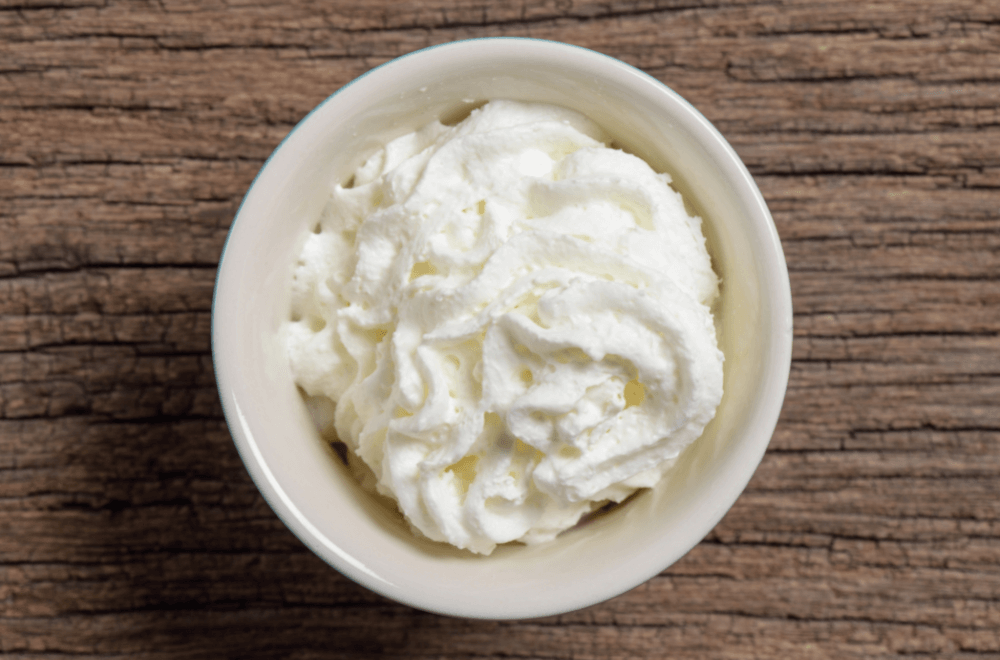 A cup of whipped cream on wooden table
