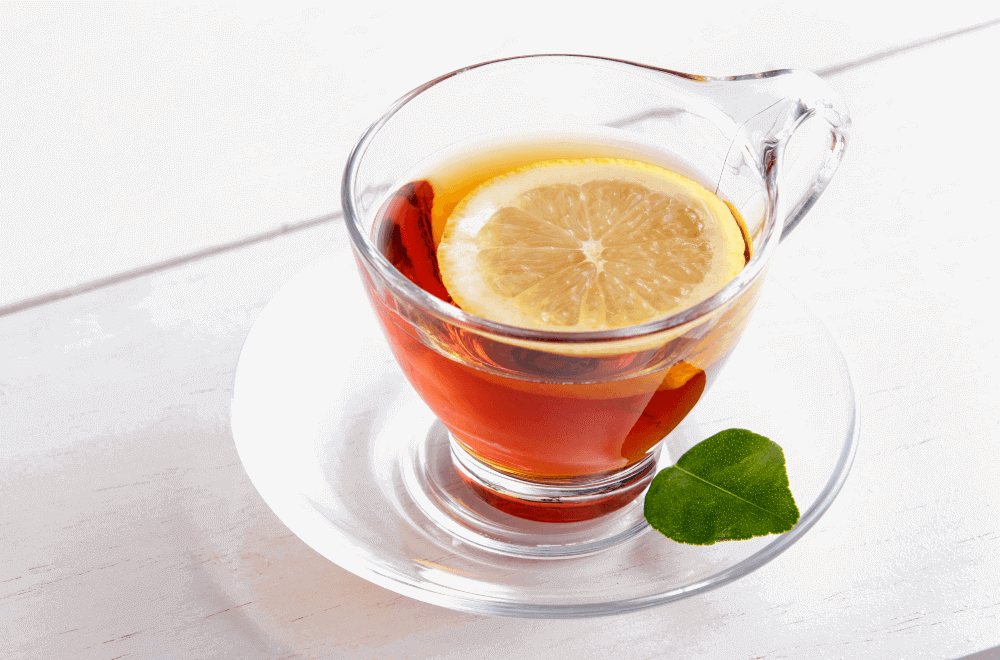 A cup of lemon tea and a lemon slice with lemon leaf