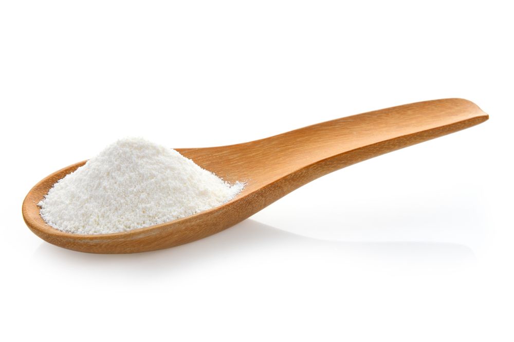 Non-dairy creamer in wood spoon on white background