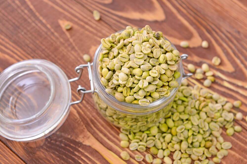 Jar with green coffee beans on table