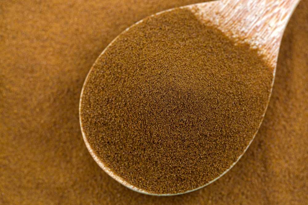 Pure instant African spray dried coffee from Robusta and Arabica coffee beans in wooden spoon