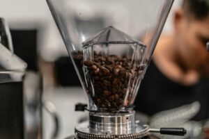 Coffee beans in a grinder hopper, shown as an illustrative coffee-making scene rather than a photo of the Encore ESP.