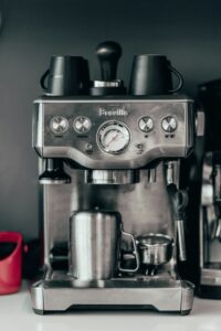 A real Breville espresso machine front panel with buttons, pressure gauge, and CLEAN/DESCALE indicator.