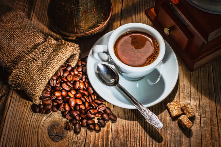 Coffee beans, a coffee grinder and a cup of coffee.