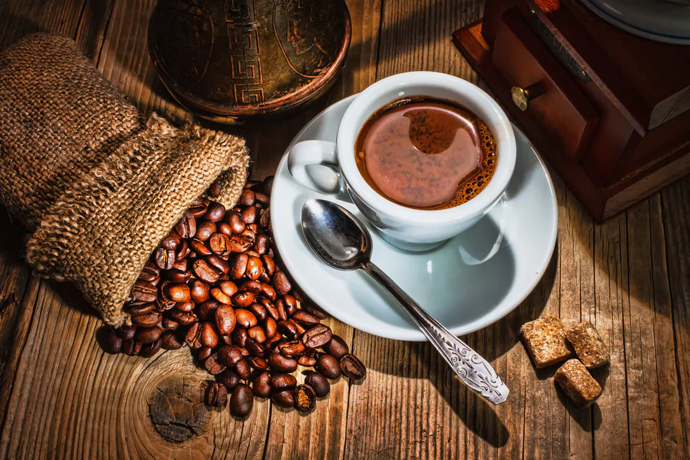 Coffee beans, a coffee grinder and a cup of coffee.