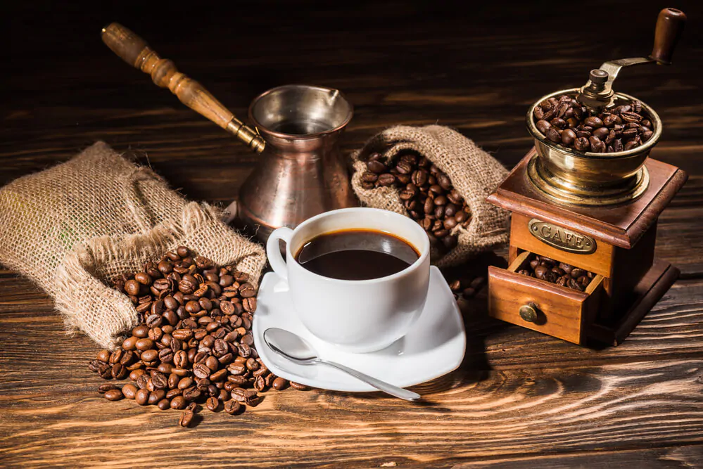 cup of coffee with coffee beans and a coffee pot