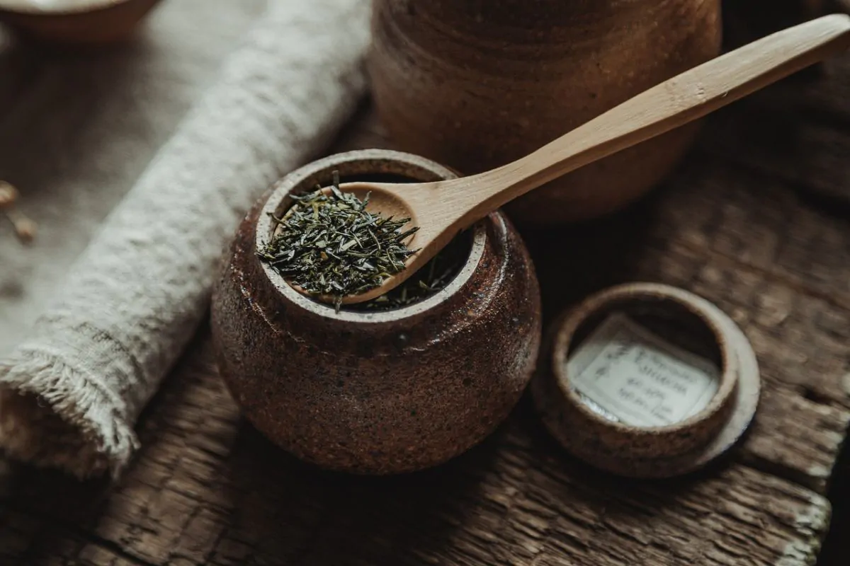 loose leaf tea in a wooden spoon at a top of jar