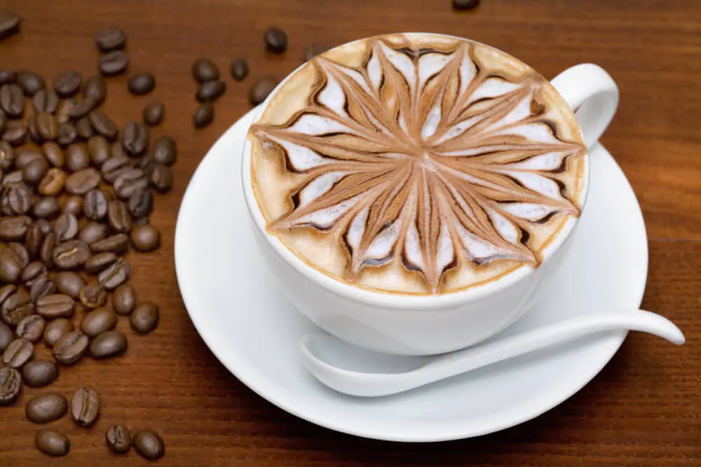 How do you keep frothed milk frothed. Top view of a cup of frothed milk with flower art.